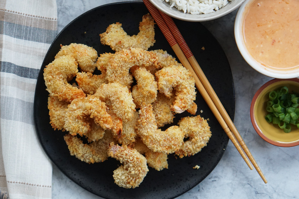 air fryer crispy shrimp with rice, bang bang sauce, and green onion.