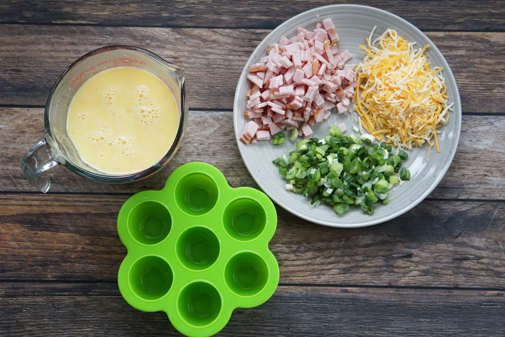 Egg mold, measuring cup full of egg mixture and plate of toppings