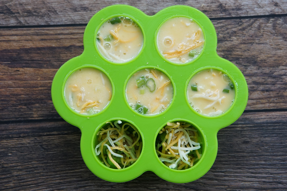 Egg bite mold partially full of scrambled egg mixture