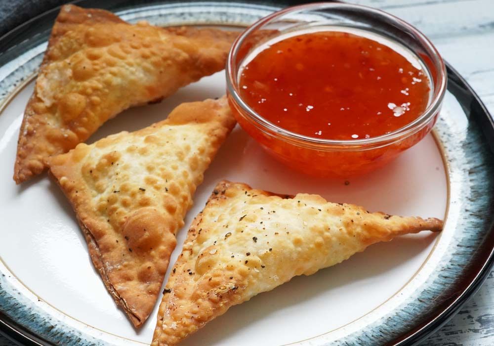 Jalapeno popper wontons on a plate with dipping sauce.