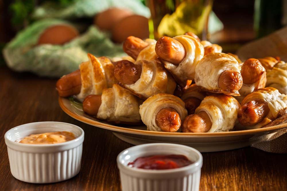 A plate of pigs in a blanket with dipping sauce