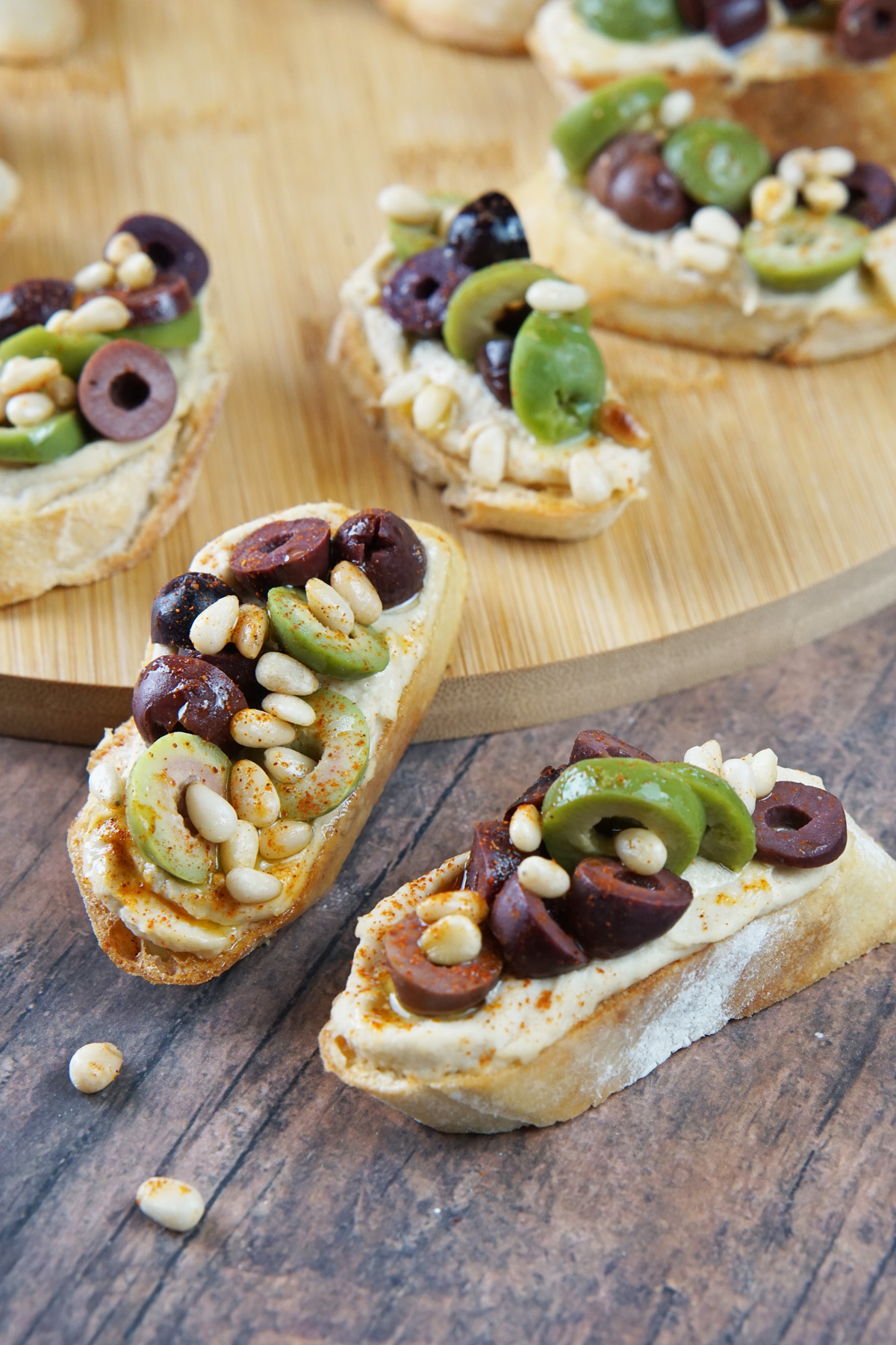 Hummus crostini with olives and pine nuts