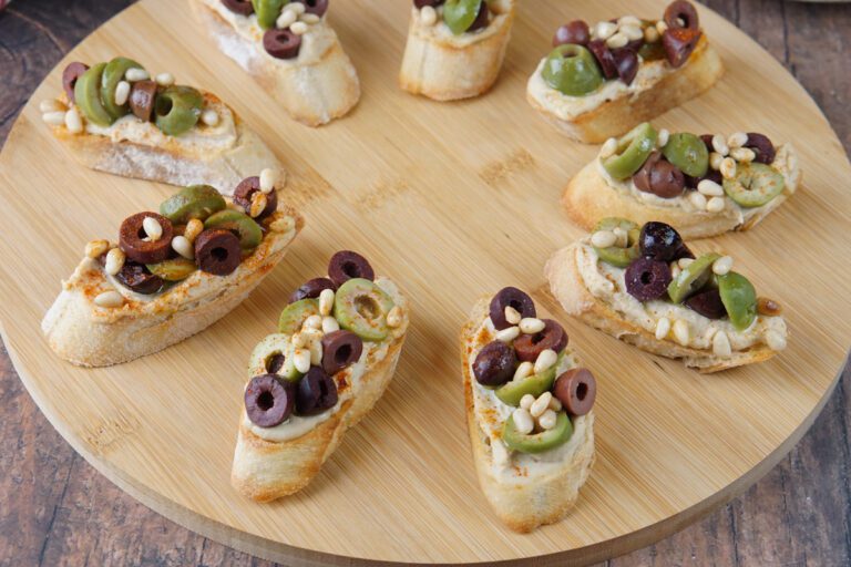 Hummus crostini with olives and pine nuts